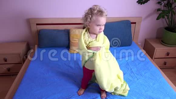 小女孩跳在被格子包裹的床上视频的预览图