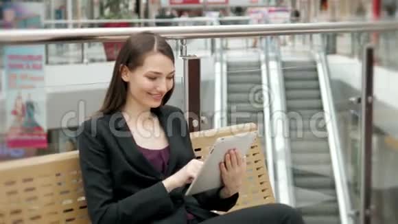 在购物中心或机场候机楼座位上现代购物者在数字平板电脑上计算视频的预览图