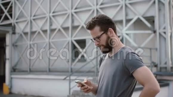 年轻时尚的商人站在街上使用智能手机戴着胡子戴着眼镜的人在和别人聊天视频的预览图