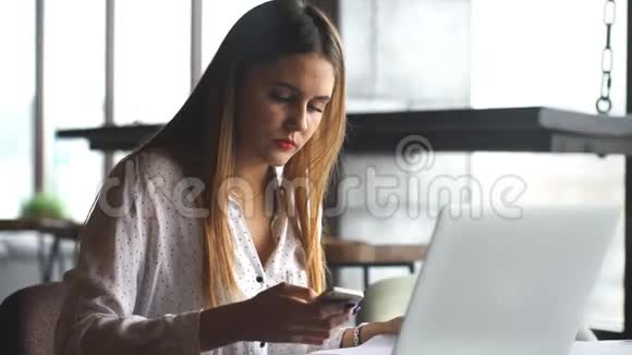穿着白色衬衫的女人在咖啡厅里思考桌上放着电脑笔记本电脑视频的预览图