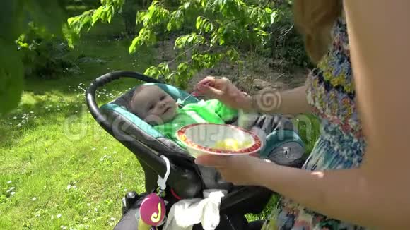 妈妈在户外的战车里喂婴儿母亲和童年4K视频的预览图