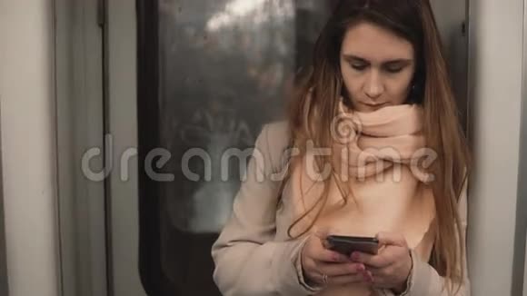 站在地铁里的年轻漂亮女人的肖像女孩使用智能手机在地铁列车上浏览互联网视频的预览图