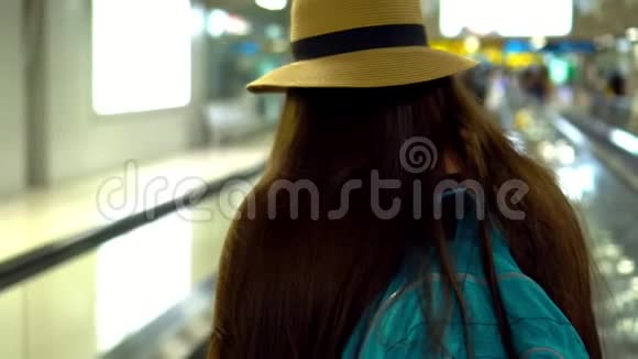 那个在机场戴草帽的年轻女孩这个女孩看着洗去了智能手机到目前为止她走上了一条道路视频的预览图