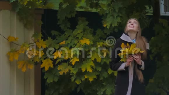 穿着黑色衣服的女孩带着一束黄色的秋叶摆着姿势视频的预览图