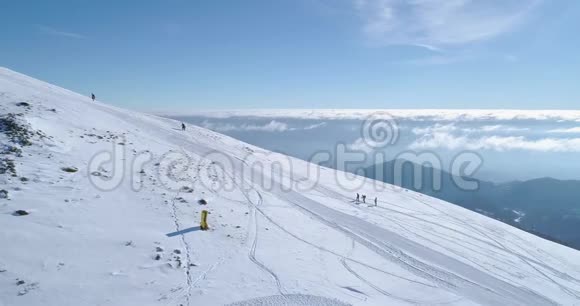 在冬季雪山滑雪跑道上人们用雪鞋徒步旅行的侧面空中晴朗的阿尔卑斯山视频的预览图