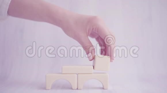 双手合拢用木块搭起玩具屋强烈的家庭观念商业增长住房视频的预览图