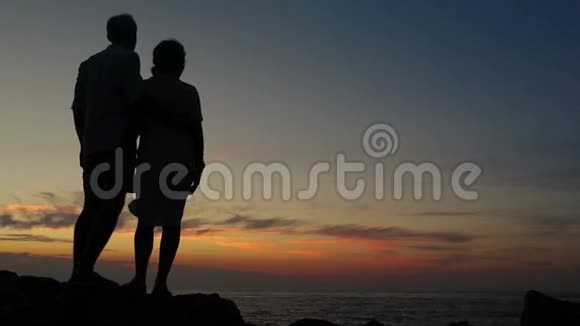 一对夫妇站在露头上看日落视频的预览图