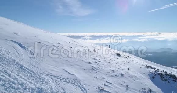 在冬季雪山滑雪跑道上人们用雪鞋徒步旅行的侧面空中晴朗的阿尔卑斯山视频的预览图