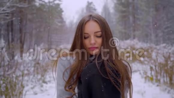 在雪地背景下的冬季公园里特写一幅时尚年轻漂亮女人的肖像看着里面的摄像机视频的预览图