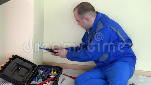 电工在公寓里拧下插座和测试电压视频的预览图