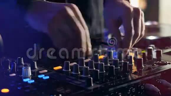 特写镜头手的DJ调整各种轨道控制在DJ混合控制台在夜总会聚会视频的预览图