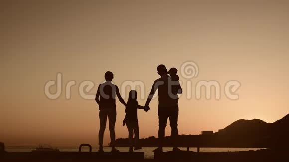 在日落时分活跃的家庭在海滩上玩得开心和享受在一起的剪影视频的预览图