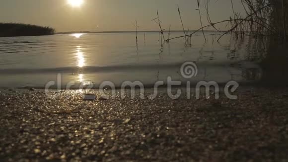 日落时海滩上的卵石海浪视频的预览图