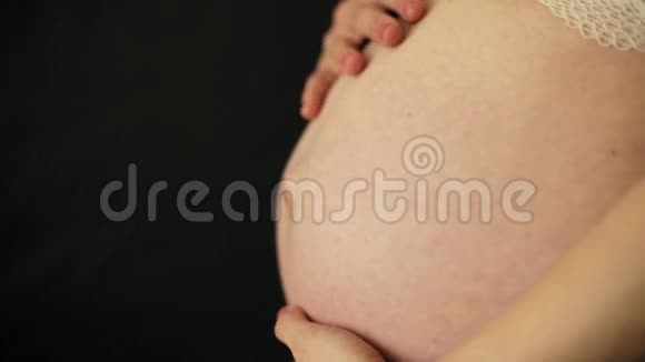 孕妇在黑色背景下抚摸肚子视频的预览图