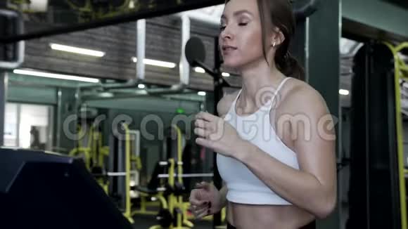 美丽的年轻女性模特在跑步机上奔跑视频的预览图