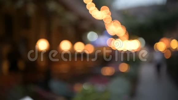 用灯泡装饰的街边咖啡馆模糊的景色和路过的人视频的预览图