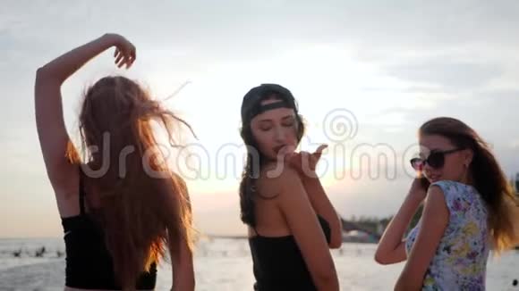 夏日的傍晚年轻的女人在度假的背景下在闪亮的大海上跳舞女孩们在河堤上玩得开心视频的预览图