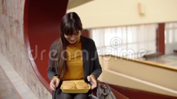 年轻女子在室内吃汉堡包视频的预览图