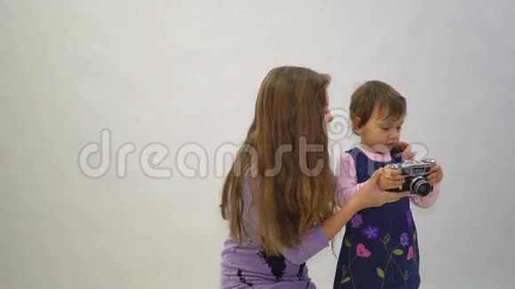 小女孩和她姐姐带着白色背景的老式照片相机视频的预览图