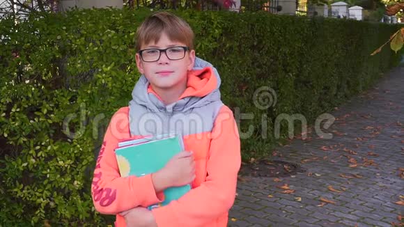 一个小学生的肖像他手里拿着一本教科书微笑着看着相机夏天结束了视频的预览图