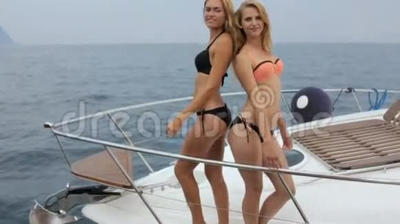 两个身穿比基尼的金发美女在游艇的船头上摆姿势视频的预览图