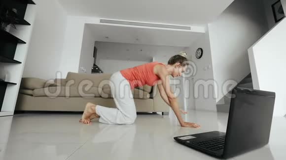 健身妇女看手提电脑在家庭训练中做健身运动视频的预览图