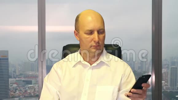 一个男人在现代办公室看电话视频的预览图