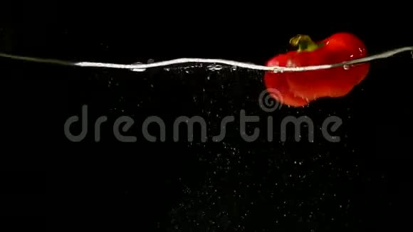 红辣椒辣椒黑背景下的蔬菜落水视频的预览图