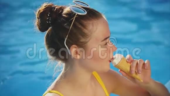 一个穿着泳衣的年轻女人在游泳池里喝着喇叭里的冰淇淋视频的预览图