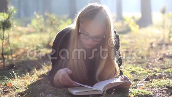 戴眼镜的漂亮女孩在森林里看书视频的预览图
