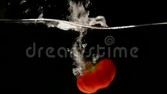红辣椒辣椒黑背景下的蔬菜落水视频的预览图