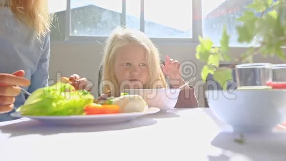 妈妈把食物从盘子里放进小女孩碗里视频的预览图