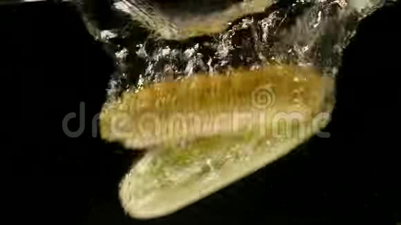 新鲜的甜玉米掉进清澈的水里溅在黑色背景上慢动作特写镜头视频的预览图