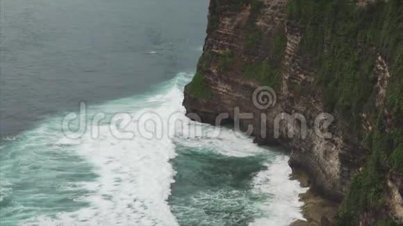 从悬崖到海洋在乌卢瓦图巴厘岛印度尼西亚多云天气悬崖和海岸线的景色视频的预览图