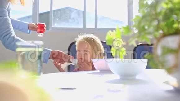 小金发女郎坐在餐桌旁妈妈给她擦嘴视频的预览图
