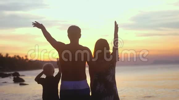年轻健康的家庭在暑假在热带海滩的日落阳光下挥动双手慢动作3840x2160视频的预览图