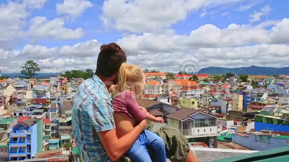 亲密父亲小女孩坐在屋顶挥手看城市视频的预览图