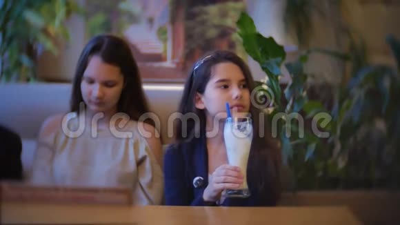 女孩喝奶昔坐在咖啡馆慢动作视频室内快餐视频的预览图