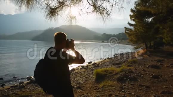 旅行者摄影师拍摄一个山湖岸边美丽的日落视频的预览图