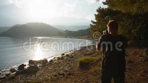 旅行者摄影师拍摄一个山湖岸边美丽的日落视频的预览图