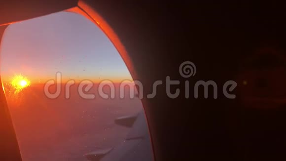 早晨通过客机窗口观看日出黎明时透过飞机窗口俯瞰云景视频的预览图