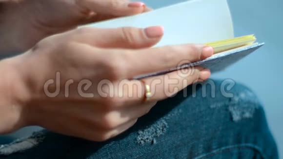 女孩正坐在街上手里拿着树叶页的记事本视频的预览图