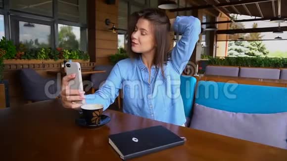 迷人的女孩用智能手机自拍慢动作喝杯咖啡视频的预览图