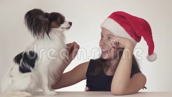 戴着圣诞老人帽子的美丽快乐的少女惊讶地享受着期待已久的礼物狗大陆玩具视频的预览图