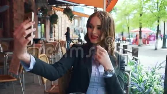 一个穿着商务服的豪华年轻女孩在咖啡馆里自拍视频的预览图