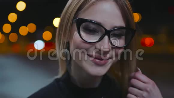 一个漂亮可爱的女孩戴着黑边眼镜晚上在商务中心附近穿着视频的预览图