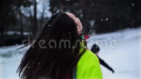 快乐的女人正试图抓住一个雪花享受冬天的户外活动色彩鲜艳的滑雪服和长裙的滑稽女孩视频的预览图