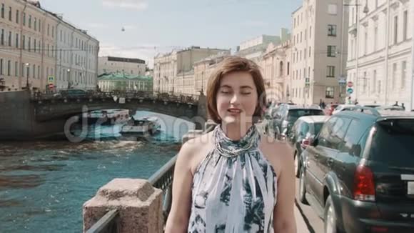 穿着斑点裙子的快乐女孩沿着老市中心的河流歌唱视频的预览图