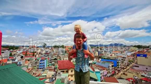 父亲紧紧抓住城市屋顶上的小女孩视频的预览图