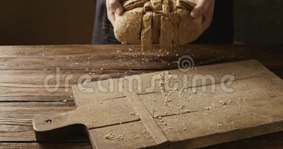 一个人把新鲜的面包片扔在旧木砧板上视频的预览图